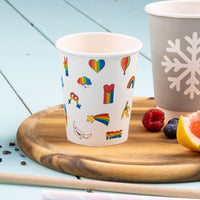Pappbecher weiß mit buntem Motivaufdruck auf Holzbrett, daneben Himbeere, Heidelbeere und Grapefruit