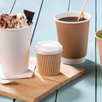 Riffelbecher klein mit weißem Deckel neben einem weißen Becher mit Dessert und einem braunen mit Kaffee